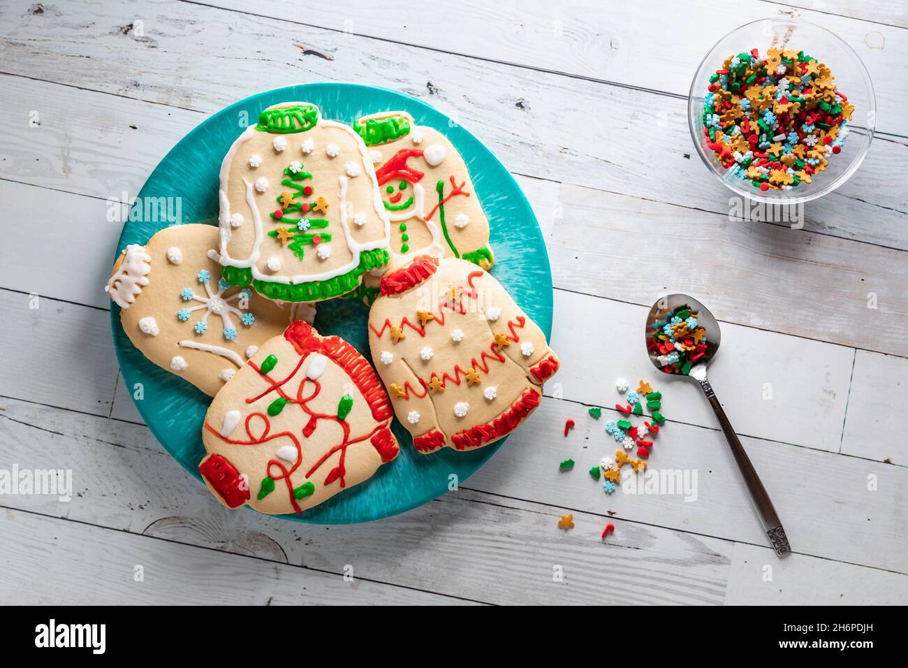 Ein Teller mit hässlichen Weihnachts-Pullover-Keksen mit einer Schüssel mit Streuseln zur Seite. Stockfoto