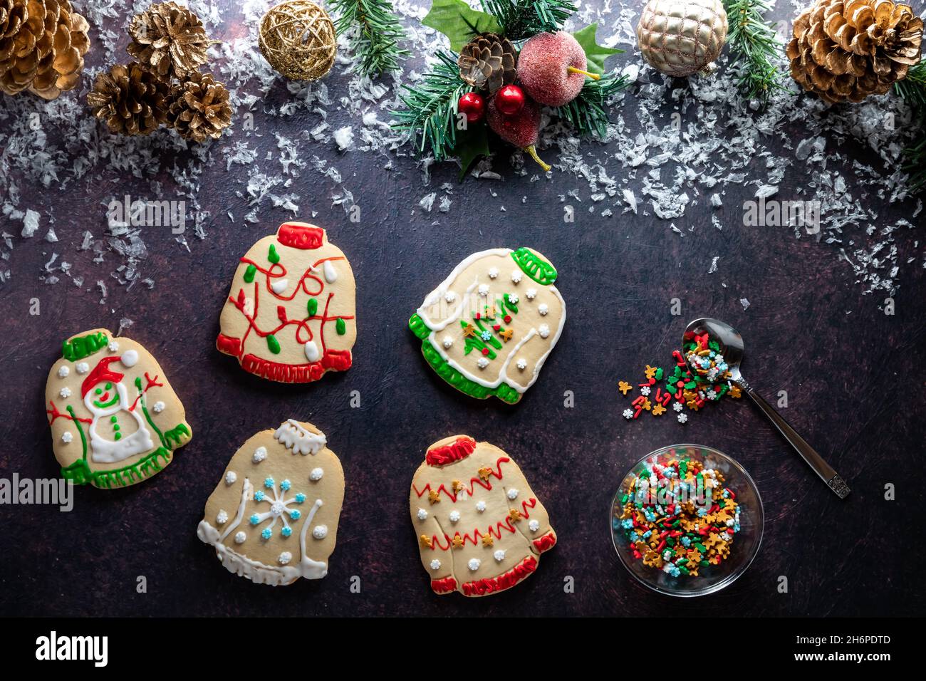 Hässliche Weihnachts-Pullover-Kekse verstreut mit Weihnachtsschmuck oben. Stockfoto