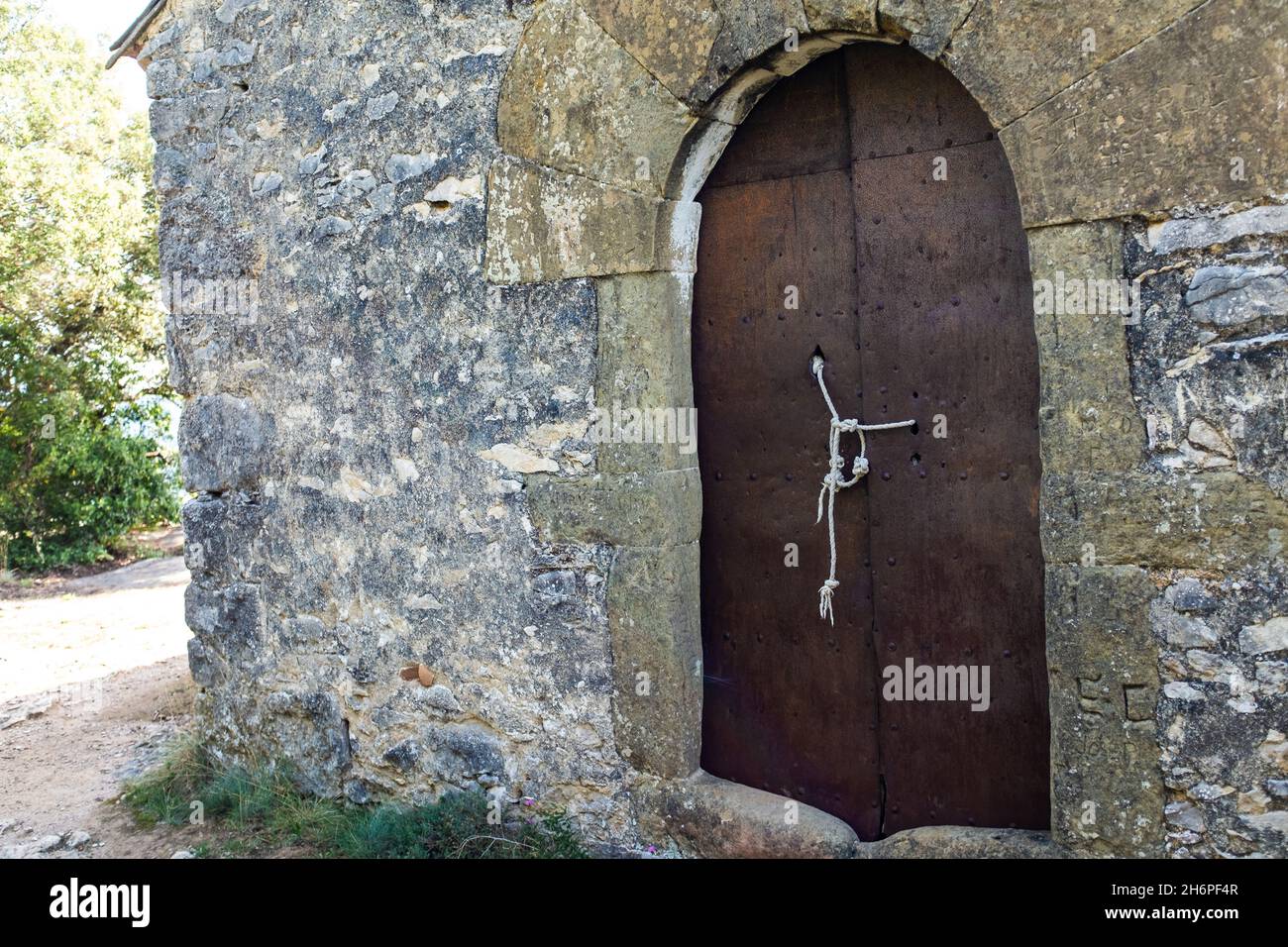 Alte geschmiedete rostige Metalltür gebunden und mit einem Seil gesichert Stockfoto