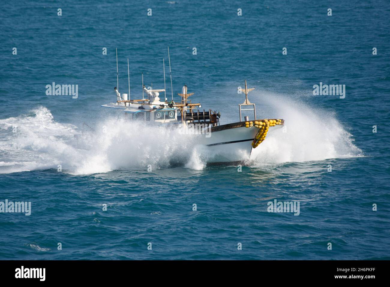 Das Fischerboot im Meer spritzt, schwimmt mit hoher Geschwindigkeit. Stockfoto