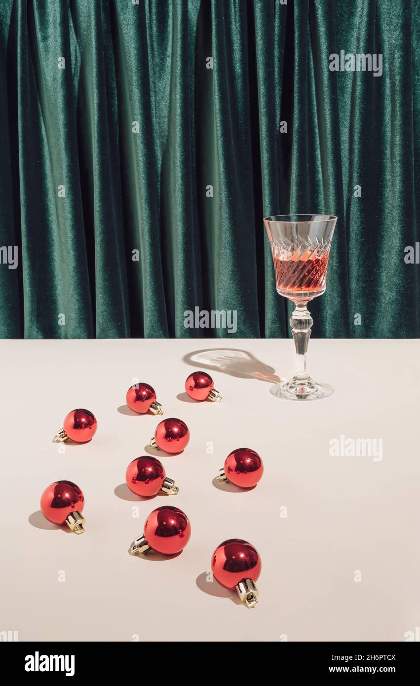 Kreative, minimalistische Weihnachts- oder Neujahrsparty-Komposition mit Vintage-Cocktailglas und roten Kugeln. Retro-Style. Stockfoto