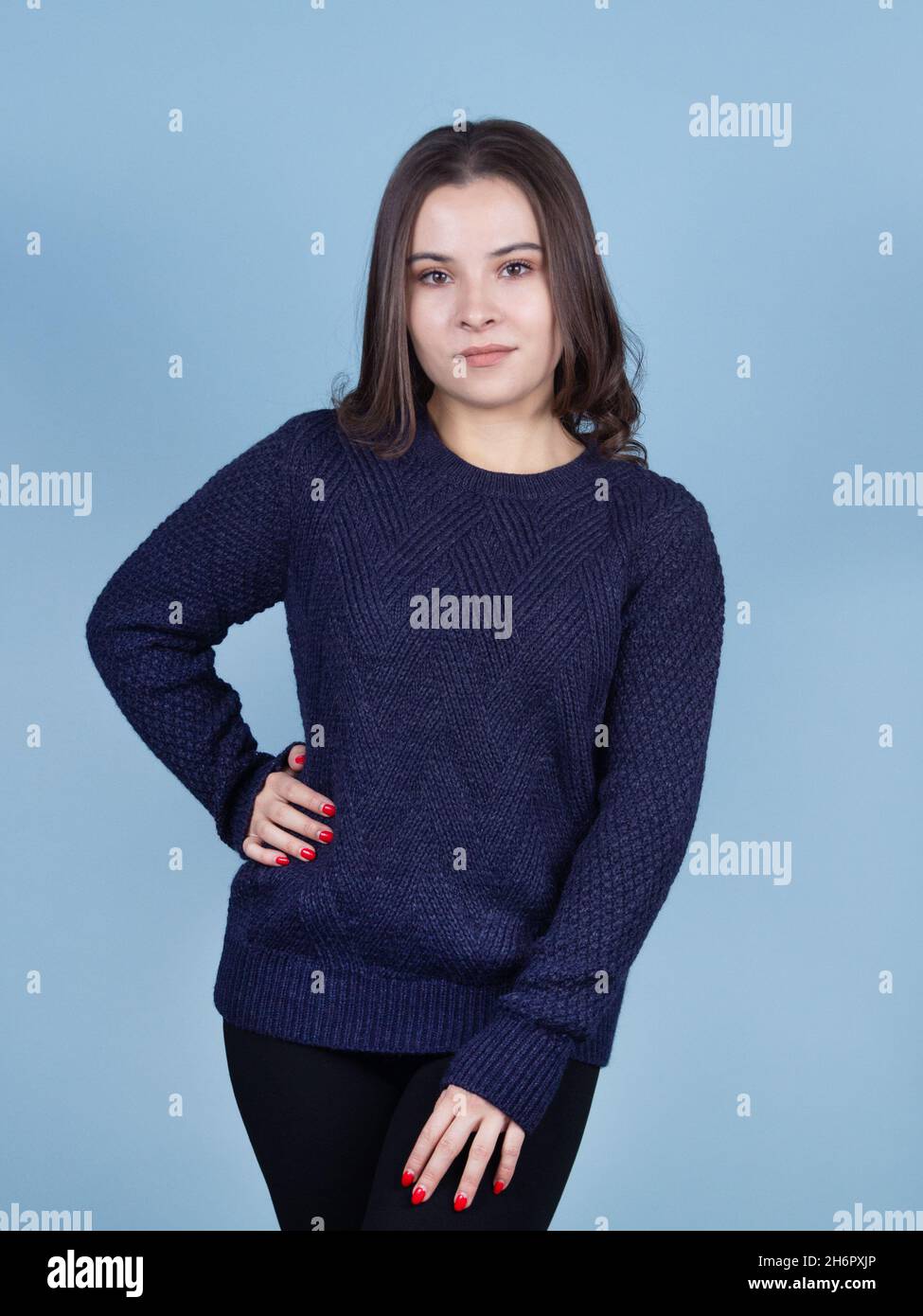 Brünette Dame in blauen Pullover auf blauem Hintergrund. Stockfoto