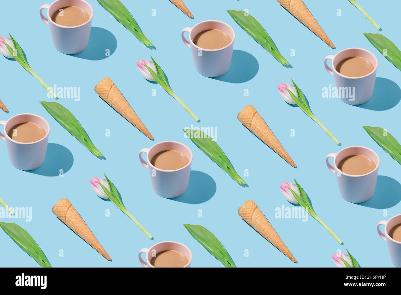 Kreatives Frühlingsmuster mit Eiszapfen, rosa Tulpen, Kaffeetassen und grünen Blättern auf blauem Hintergrund. Stockfoto