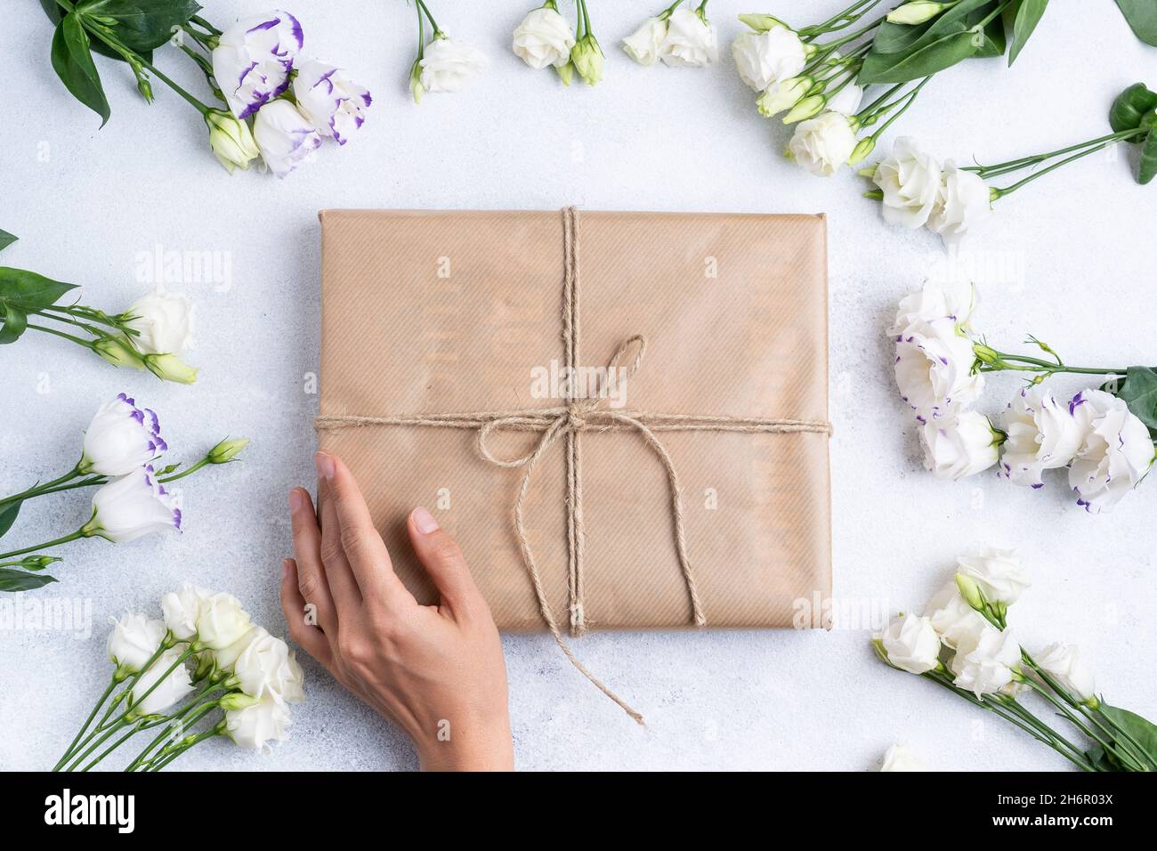 Die Zusammensetzung der Blumen und Taschen. Ein Geschenk und Blumen auf einem rosa Hintergrund. Frauentag, ein Feiertag. Flache Sonnenliege, Draufsicht, Kopierbereich. Stockfoto