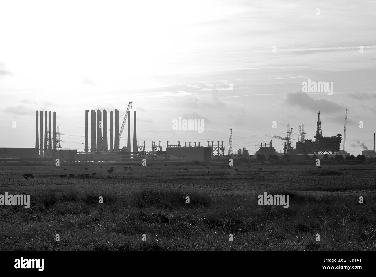 Schwarz-Weiß-Bild der Ölplattform Brent-Alpha, die demontiert wird, und Windturbinenstangen für Seagreen am Able Seaton Port, Teesside Freeport. Stockfoto