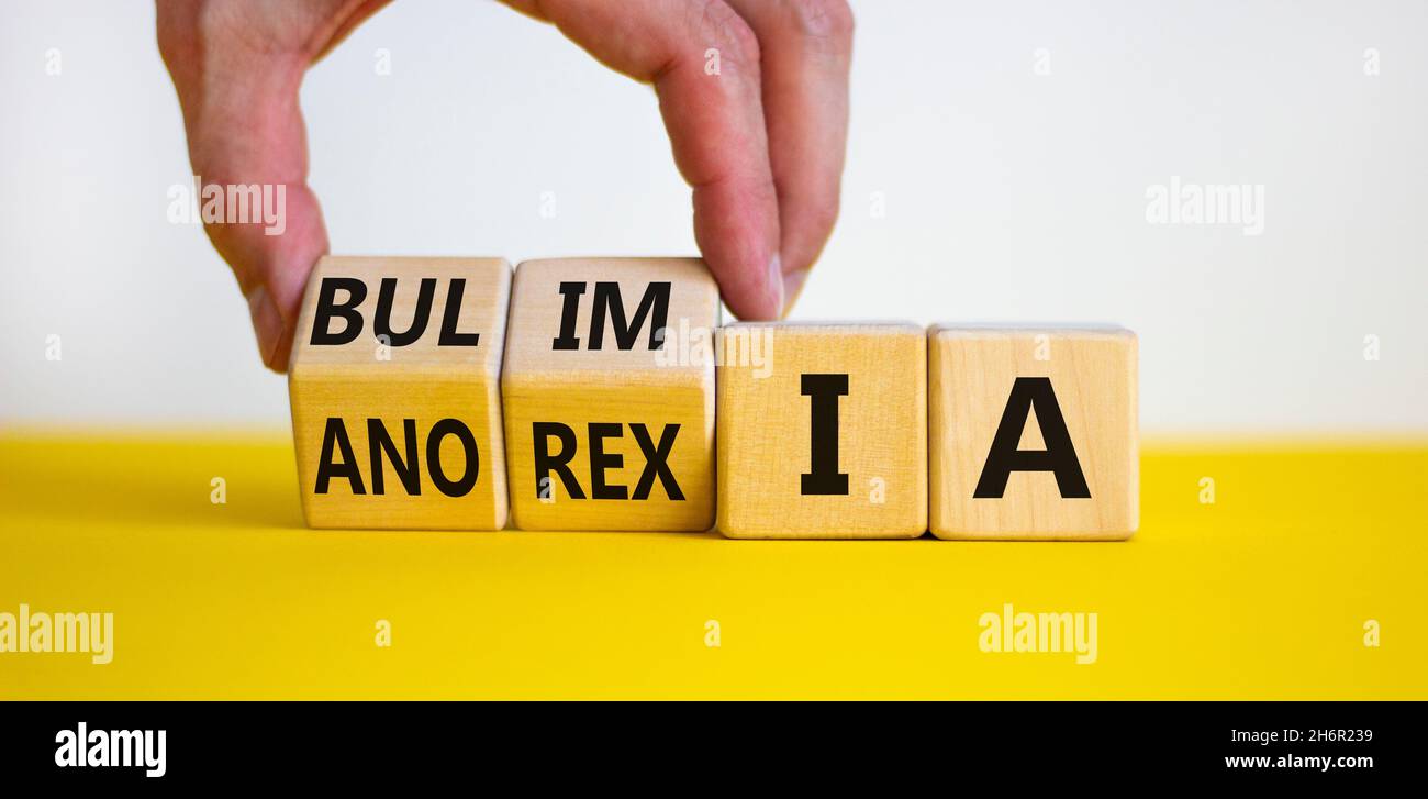 Bulimie oder Anorexie-Symbol. Doktor dreht Holzwürfel und ändert das Wort Anorexie in Bulimie. Schöner gelber Tisch, weißer Hintergrund, Kopierraum. Stockfoto