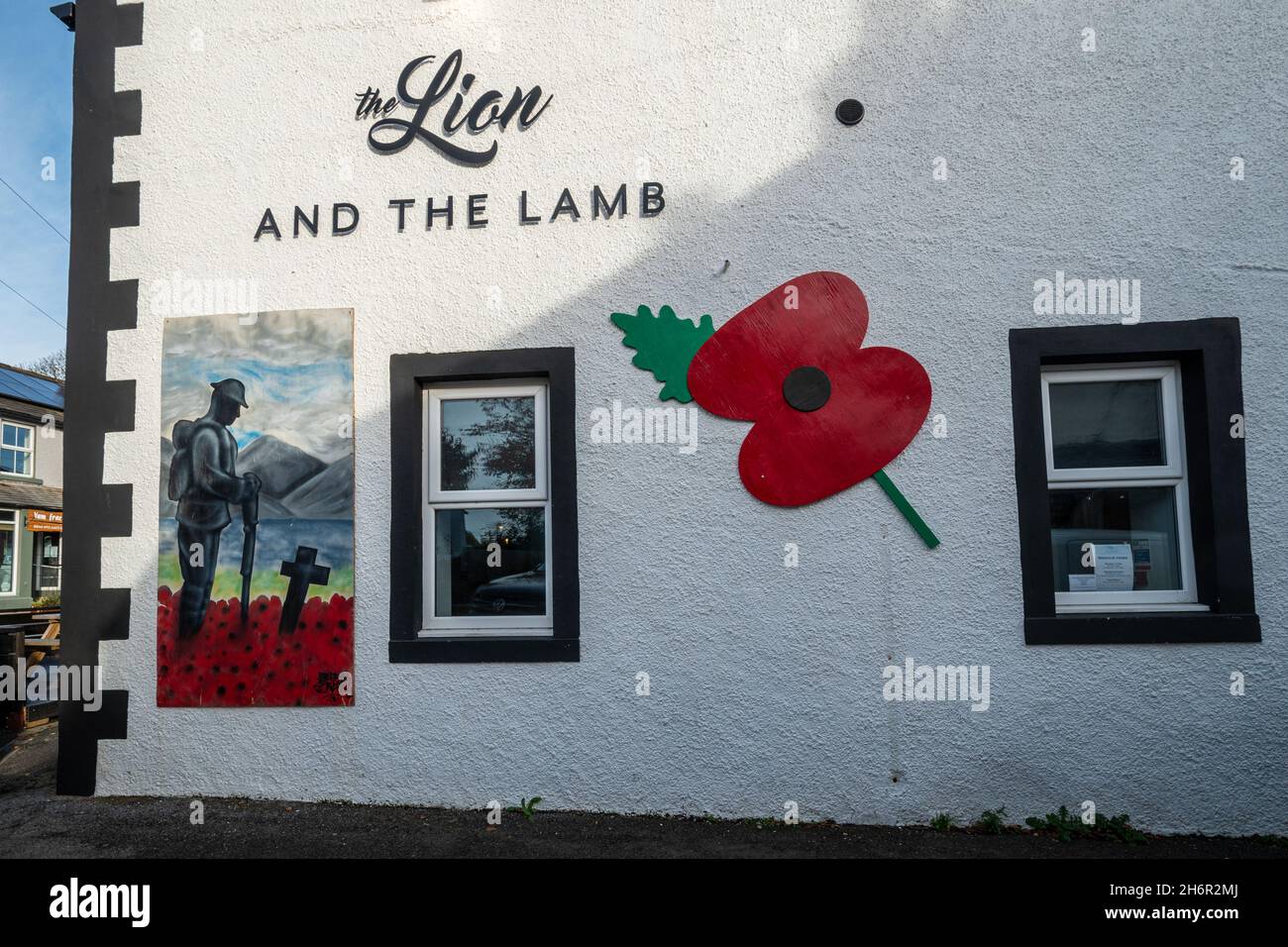 Gedenken an Mohnblumen und Gemälde an einer Kneipwand, der Löwe und das Lamm im Dorf Gosforth, Cumbria, Großbritannien, anlässlich des Waffenstillstandstages, dem 2021. November Stockfoto