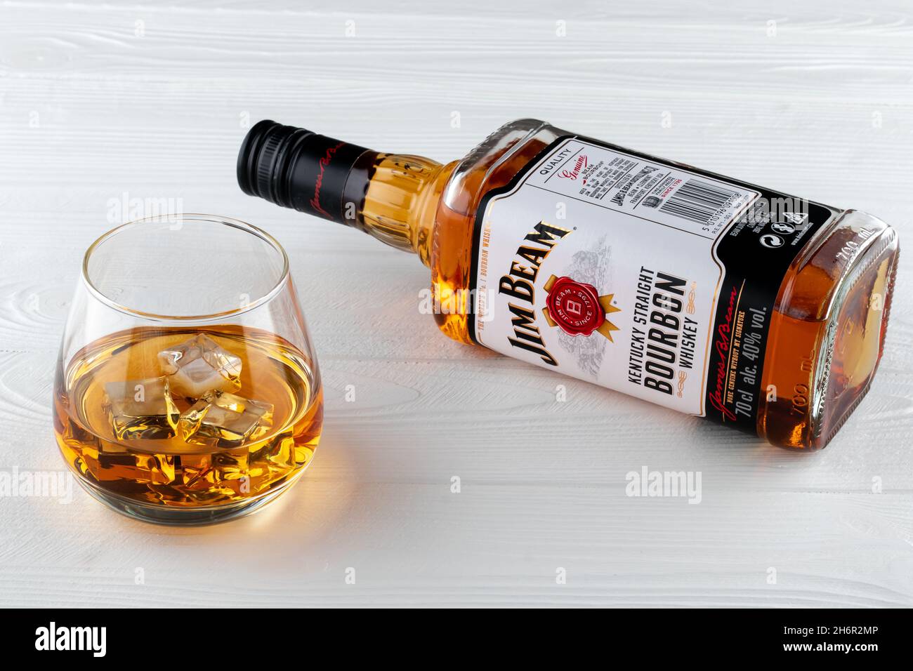 Volle Flasche Jim Beam auf weißen Holzbrettern. Ein Glas Bourbon mit Eis. Starkes Getränk. Alte Whiskey-Marke. Illustratives Editorial Stockfoto