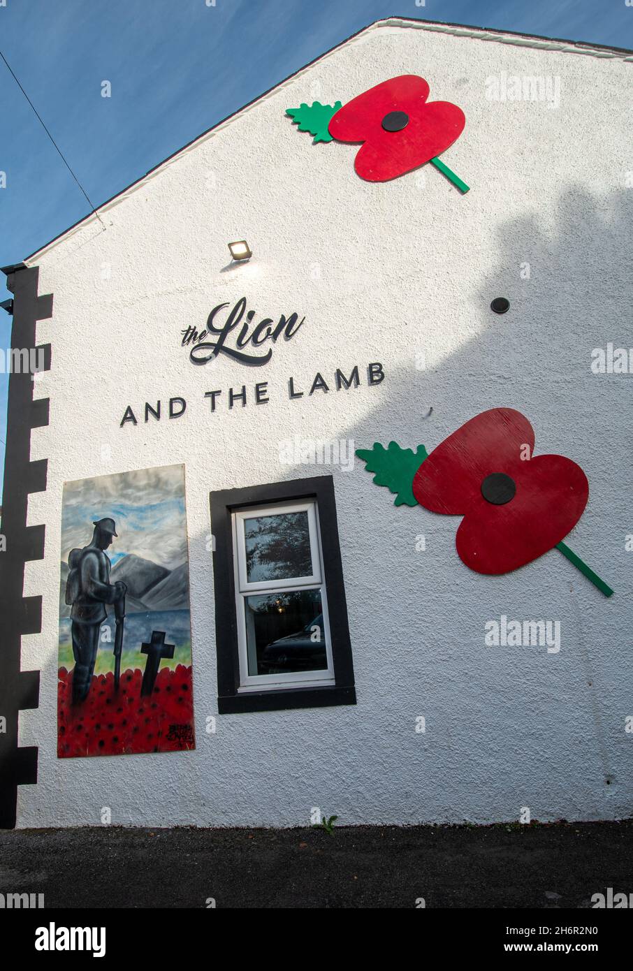 Gedenken an Mohnblumen und Gemälde an einer Kneipwand, der Löwe und das Lamm im Dorf Gosforth, Cumbria, Großbritannien, anlässlich des Waffenstillstandstages, dem 2021. November Stockfoto