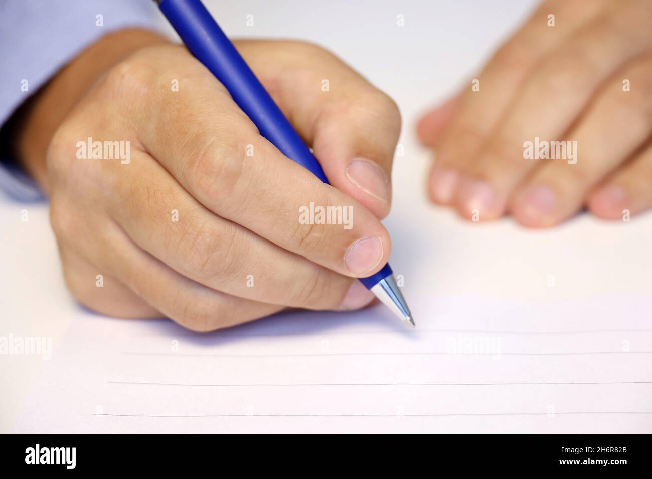 Männliche Hand mit Stift, Mann in blauem Hemd signiert das Papier. Konzept des Angestellten, des Geschäftsmannes, des Vertragsabschlusses Stockfoto