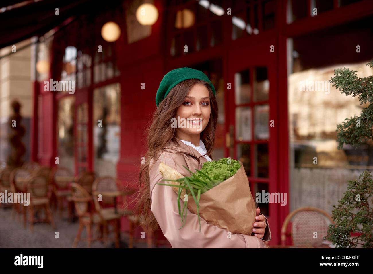 Öko-Shopping. Papiertüte mit Lebensmitteln mit Brot und Gemüse in den Händen der jungen kaukasischen Frau Stockfoto