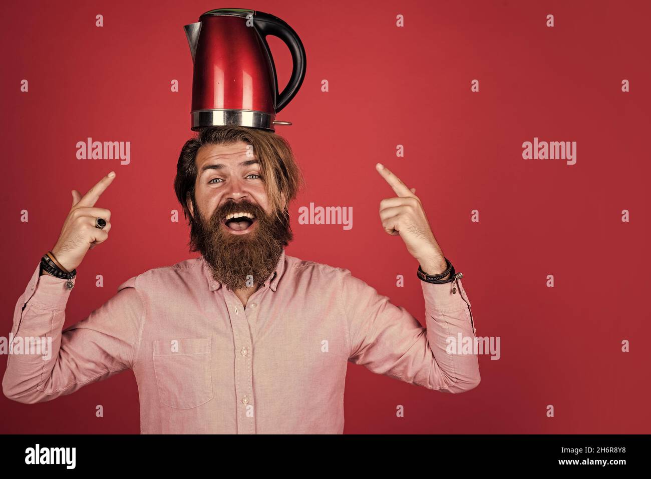 Brutaler kaukasischer Hipster mit Bart im Hemd halten Wasserkocher, modernes Leben Stockfoto