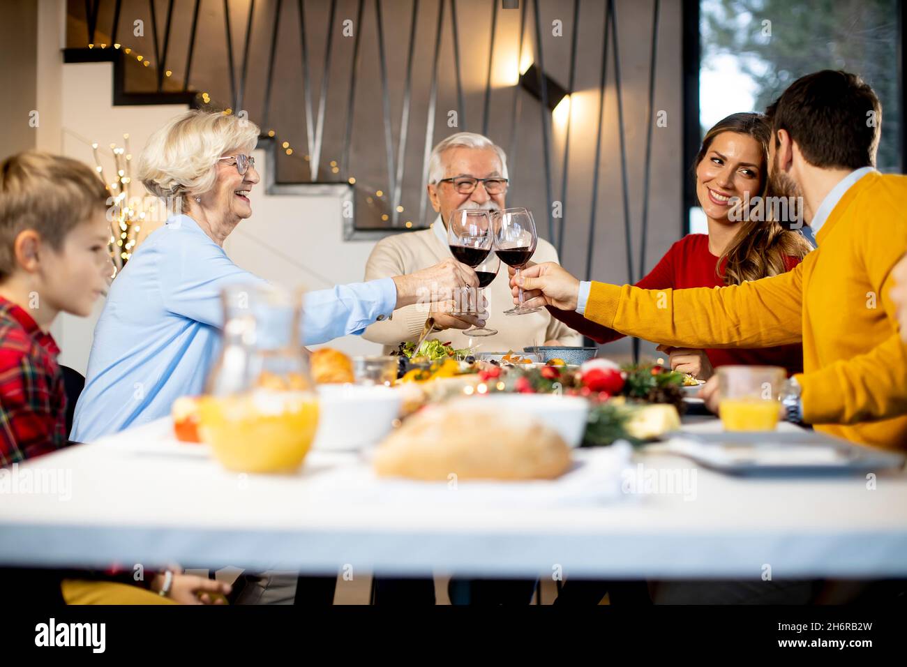 Glückliche Familie, die zu Hause ein Abendessen mit Rotwein zu sich nehmen kann Stockfoto