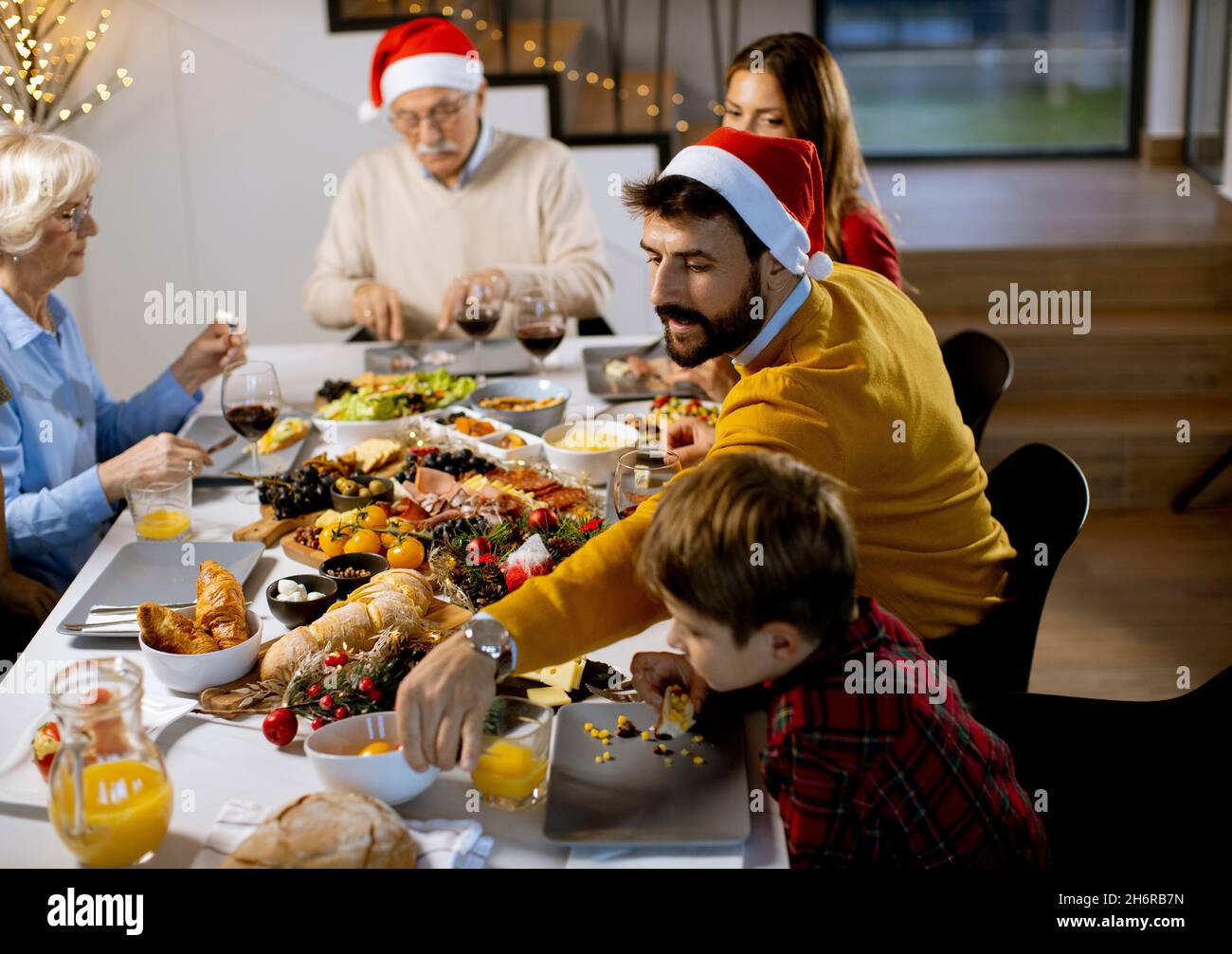 Glückliche Familie mit mehreren Generationen, die zu Hause das neue Jahr am Tisch feiert Stockfoto