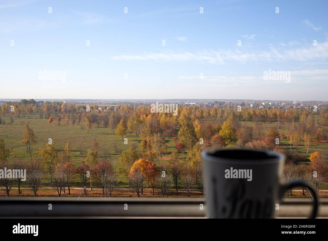 tasse Tee stehen auf der Brüstung des Fensters vor dem Hintergrund des Herbstpanoramas der Stadt Stockfoto