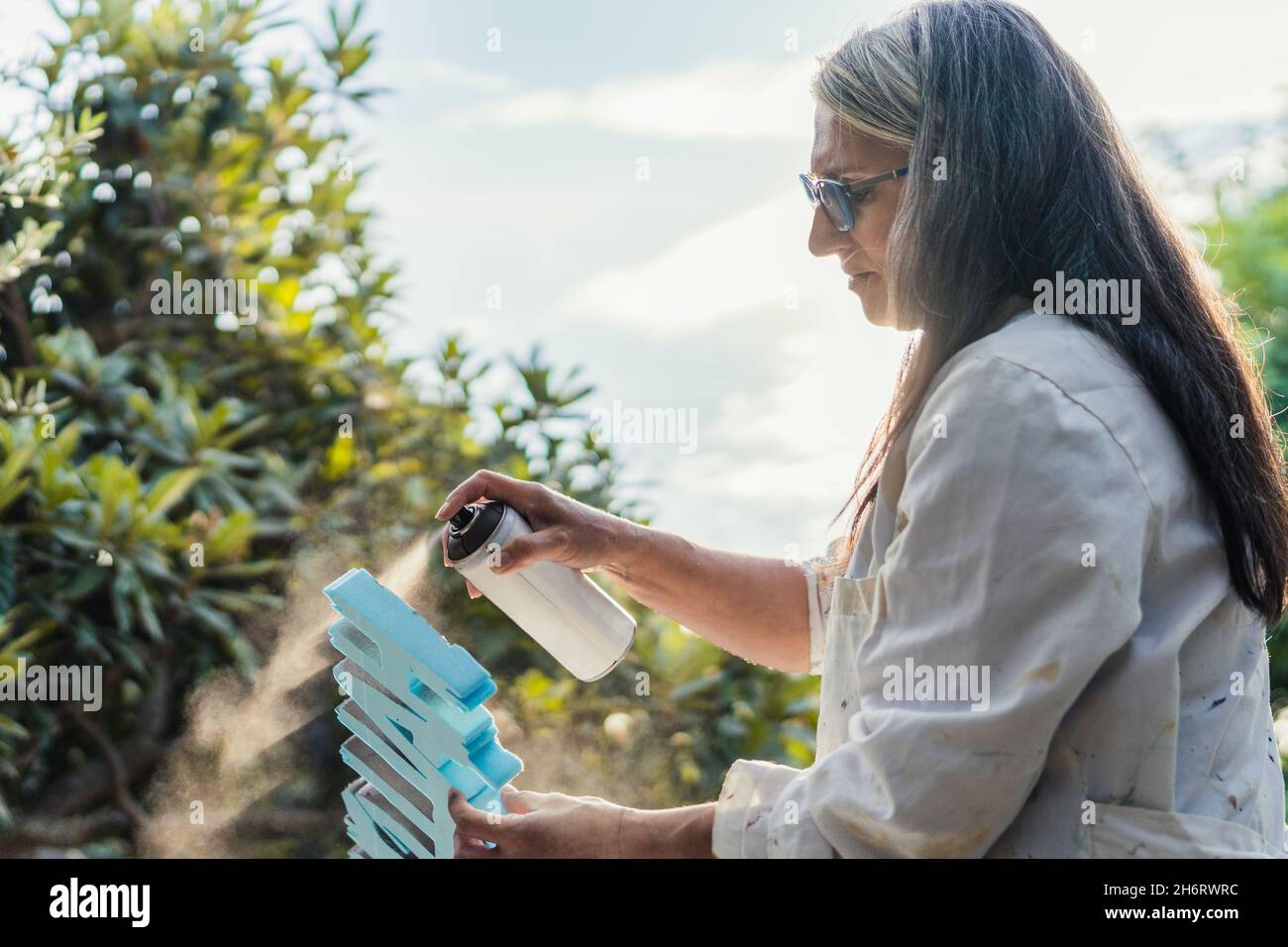 Frau malen Polystyrol Buchstaben mit Farbe auf Spray im Freien Stockfoto