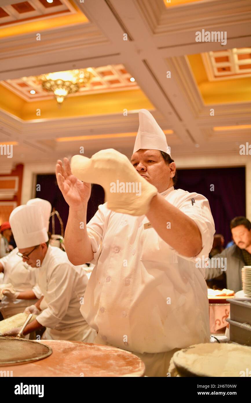 Ein erfahrener und fokussierter Koch streckt den Teig auf eine Gourmet-Pizza bei einer speziellen Konferenz auf der CES, Las Vegas, NV, USA Stockfoto