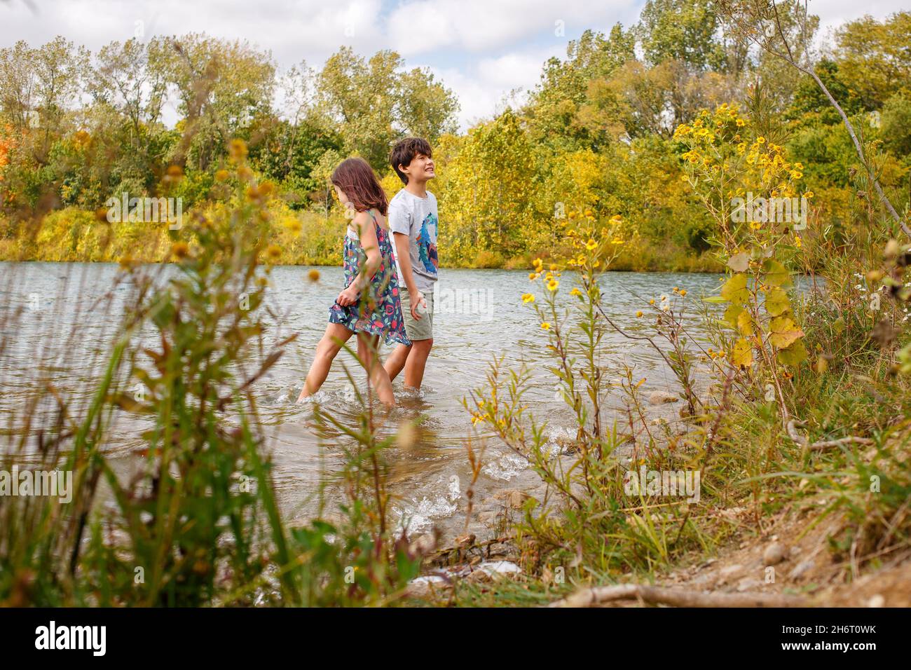 Zwei Kinder glücklich breit zusammen in einem von Bäumen gesäumten See im Sommer Stockfoto
