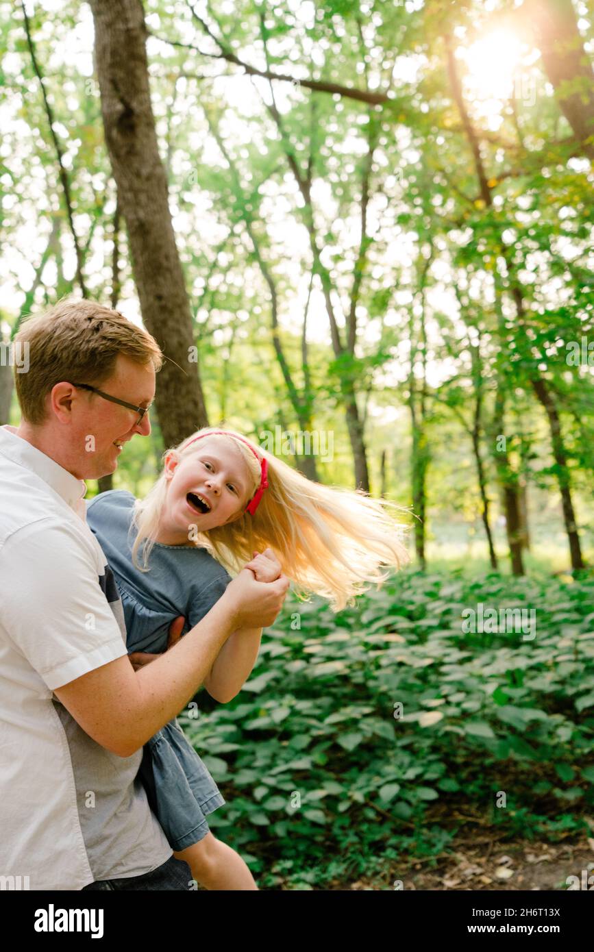 Beschnittene Ansicht eines Vaters und einer Tochter, die im Wald tanzen Stockfoto