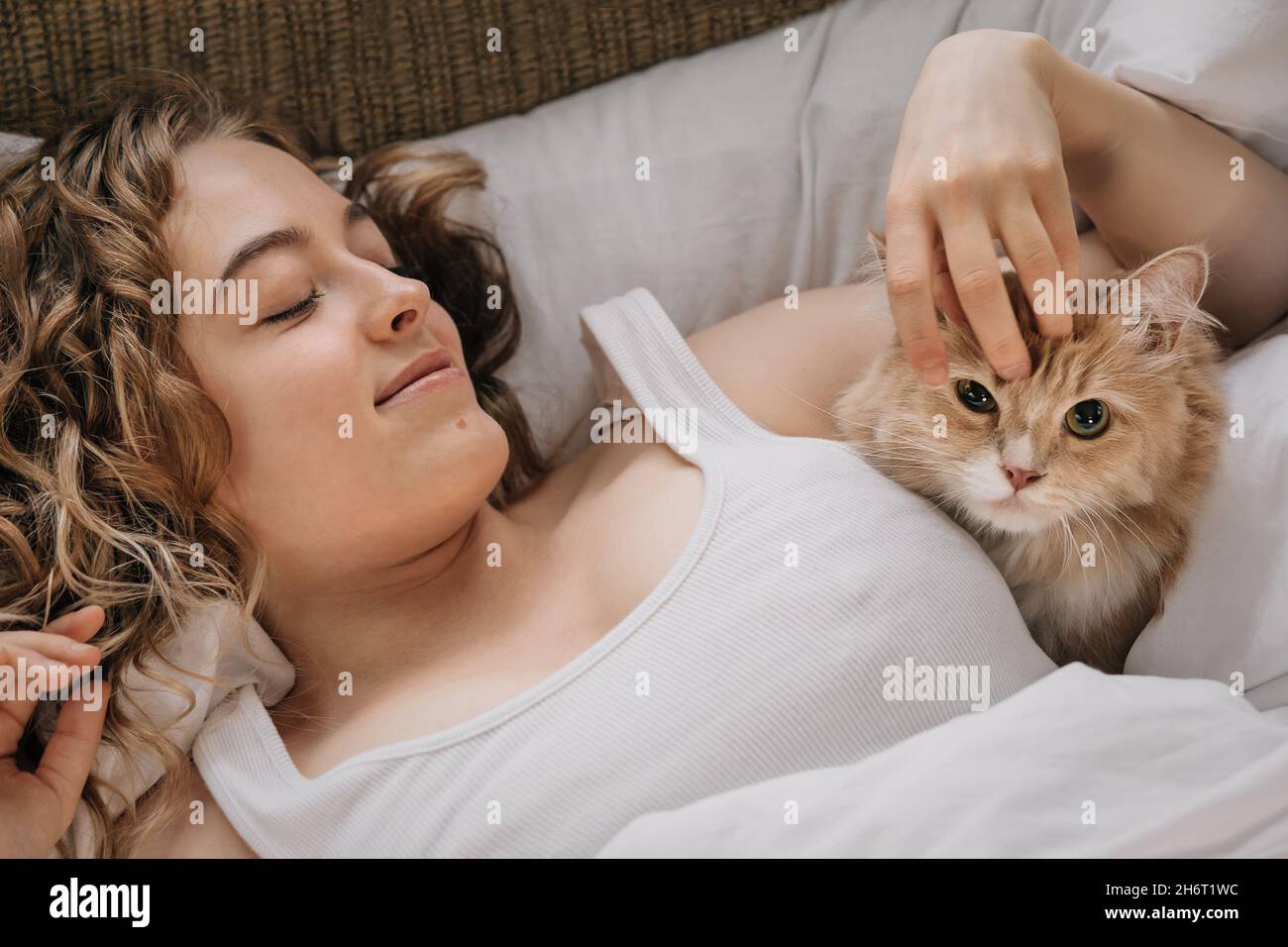 Junge Frau und Ingwerkatze im Anhänger. Stockfoto