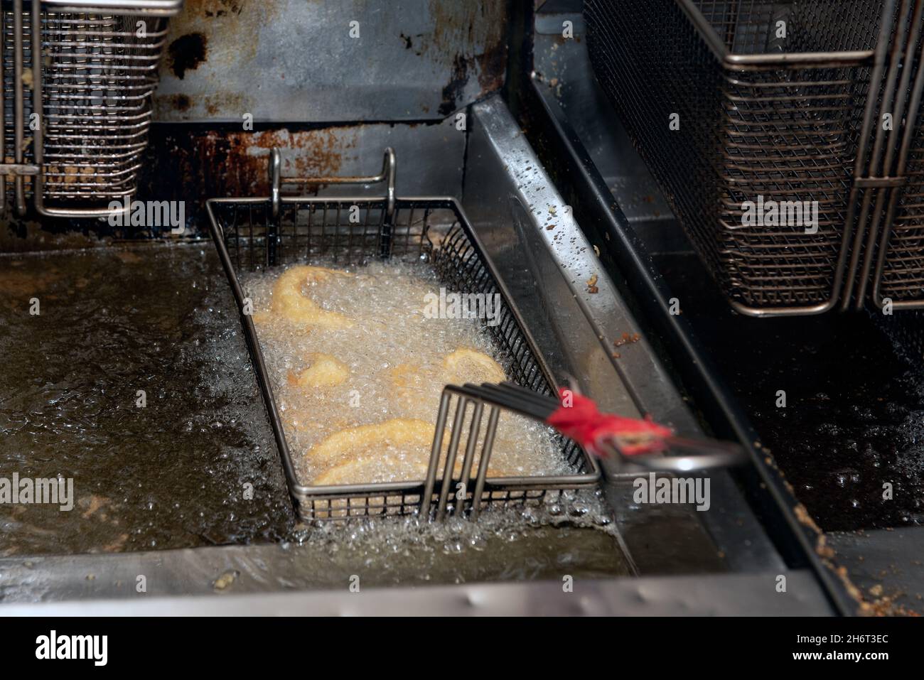 Calamari-Ringe sizeln im brüchenden heißen Öl, während sie in der Restaurantküche kochen. Stockfoto