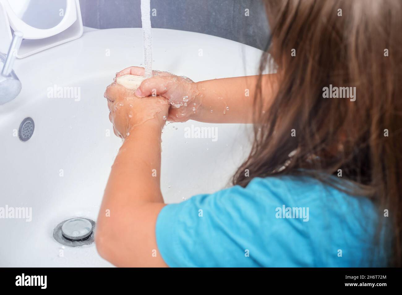 Das Kind wäscht ihre Hände mit Seife unter fließendem Wasser im Badezimmer Stockfoto
