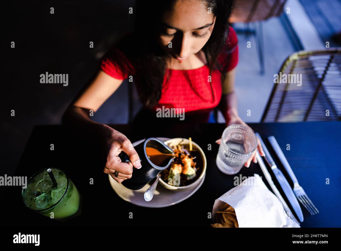 Junge Asiatische Frau Gießt Brühe Über Tortilla-Suppe-Zutaten Im Mexikanischen Restaurant Stockfoto