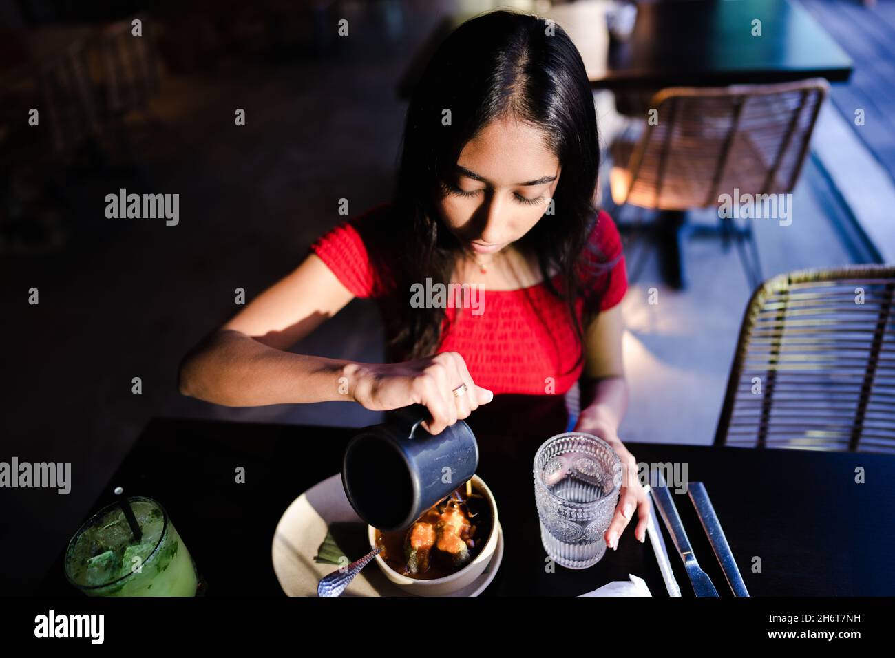 Junge Asiatische Frau Gießt Brühe Über Tortilla-Suppe-Zutaten Im Mexikanischen Restaurant Stockfoto