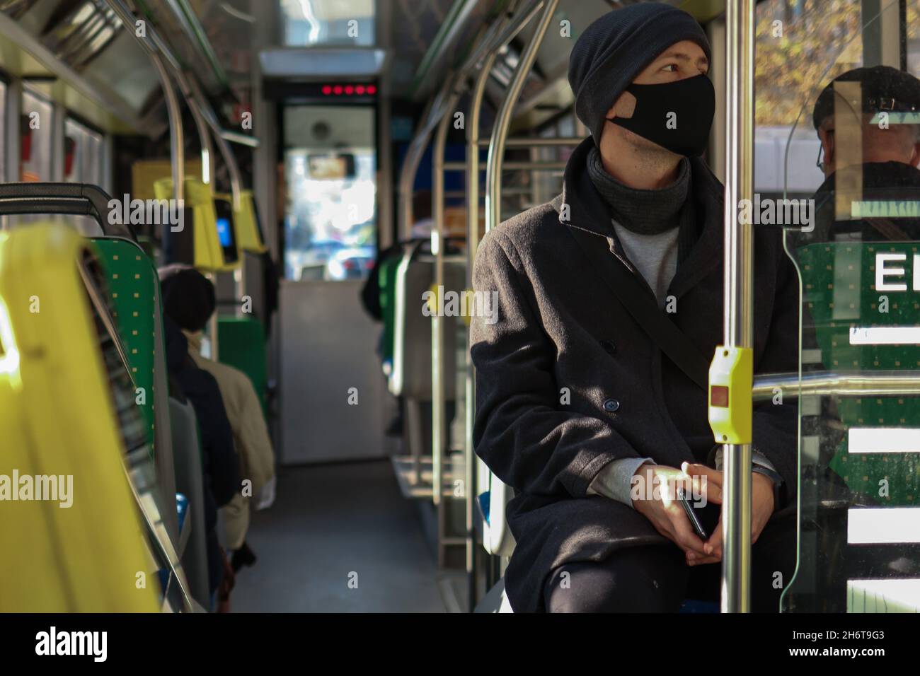 Europäischer Mann mit Gesichtsmaske, der mit dem Bus in öffentlichen Verkehrsmitteln unterwegs ist. Sicherheitsvorkehrungen während einer covid-19-Pandemie. Stockfoto