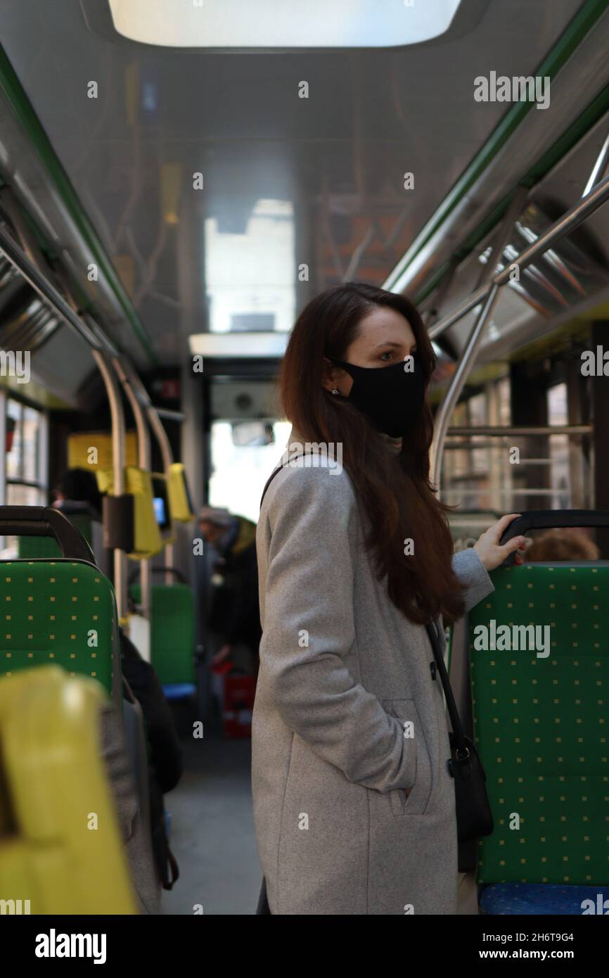 Eine junge Frau mit Atemschutzmaske reist aufgrund einer Coronavirus-Pandemie mit öffentlichen Verkehrsmitteln. Sicherheitsvorkehrungen in Bussen Stockfoto