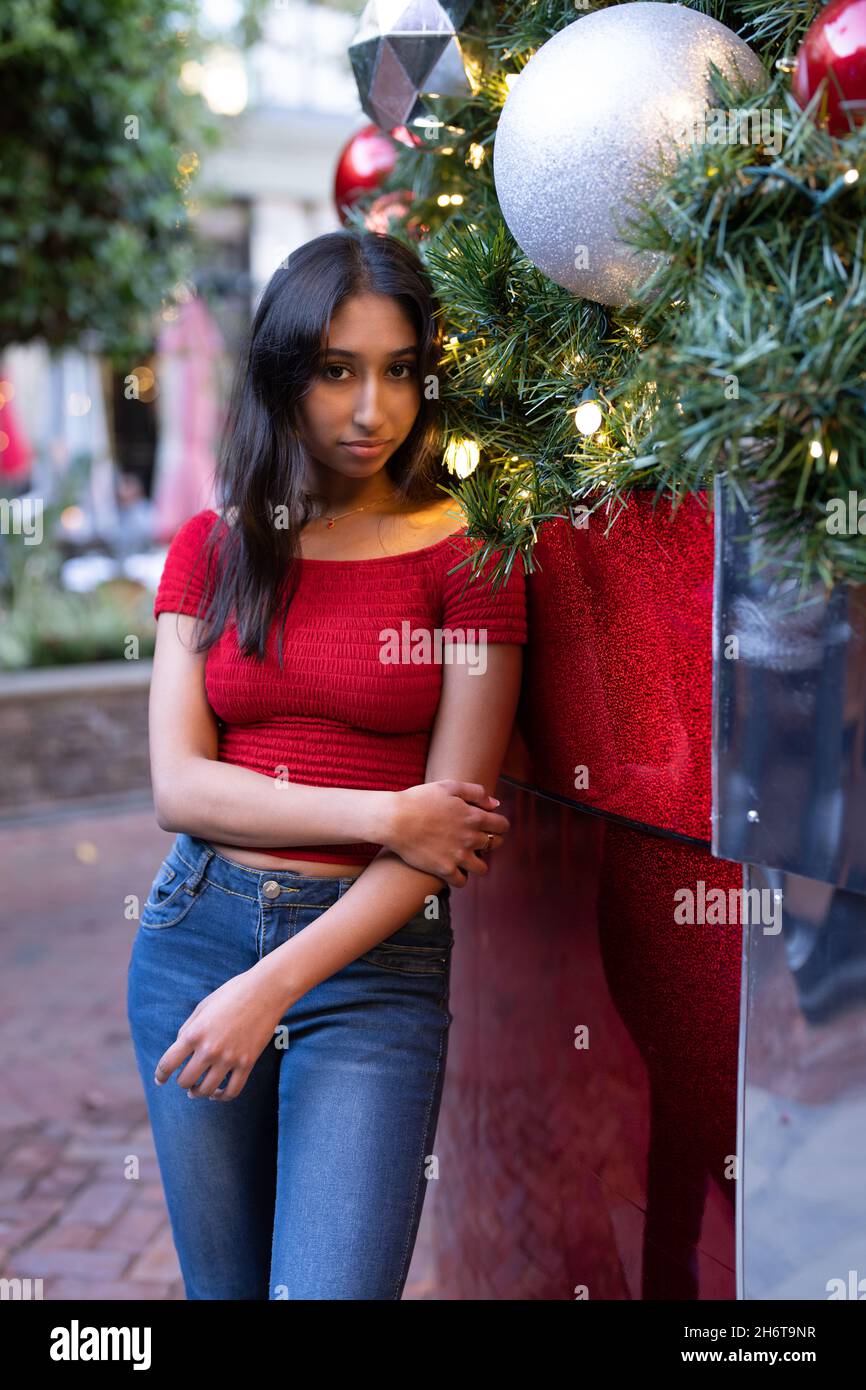 Junge Frau, die neben dem riesigen Weihnachtsbaum steht Stockfoto