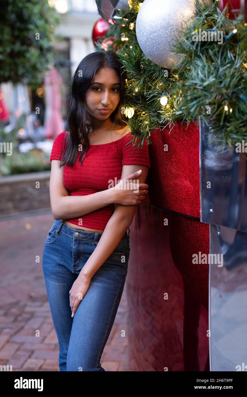 Junge Frau, die neben dem riesigen Weihnachtsbaum steht Stockfoto