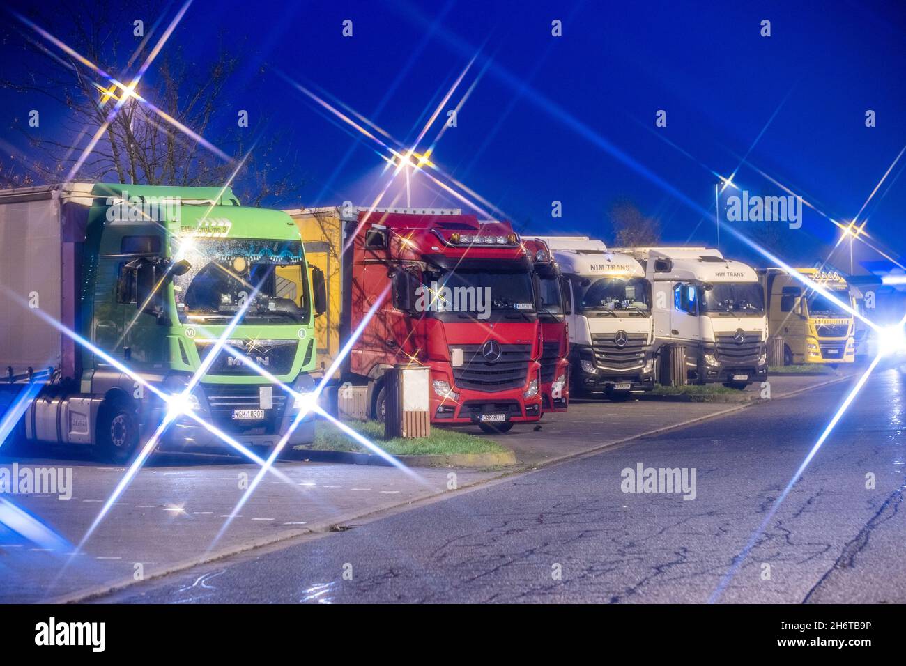 Neukloster, Deutschland. November 2021. Ein Auto fährt an geparkten Langstrecken-LKWs am Autobahnzubringer Fuchsberg vorbei. Der europaweite Lkw-Fahrer-Mangel macht sich auch bei Transportunternehmen im Nordosten bemerkbar. Quelle: Jens Büttner/dpa-Zentralbild/dpa/Alamy Live News Stockfoto