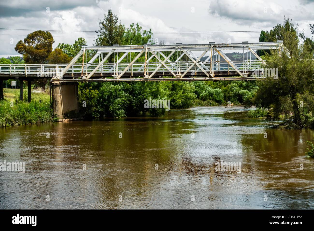 Der geschwollene Macdonald River, der unter der Holz- und Eisenbrücke von Dare Truss in Bendemeer NSW Australia fließt, Stockfoto