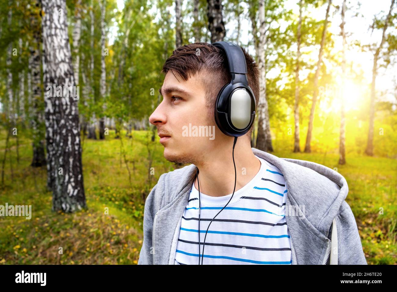 Junger Mann mit Kopfhörern hört die Musik im Wald Stockfoto