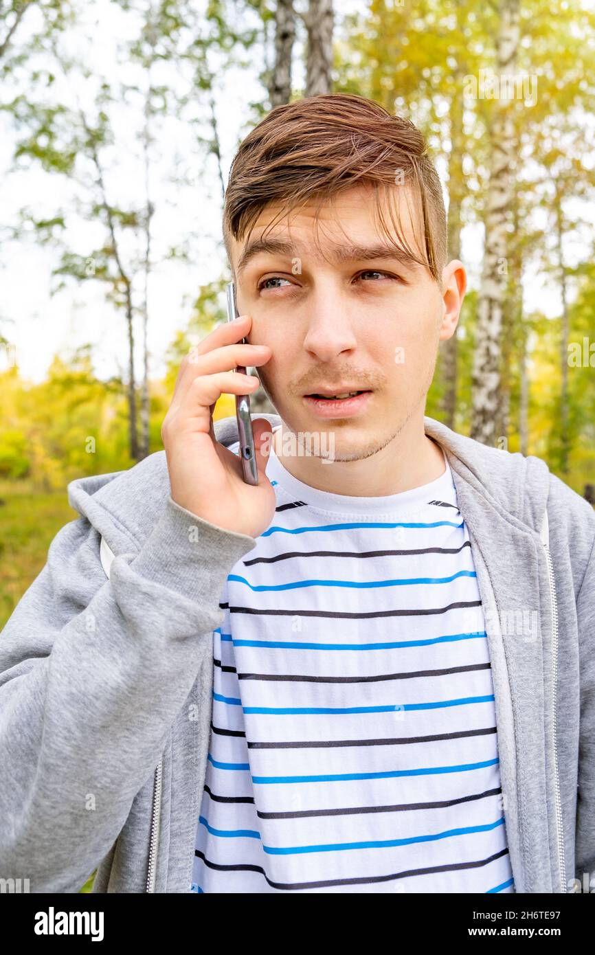 Junger Mann mit Mobiltelefon im Herbstwald Stockfoto