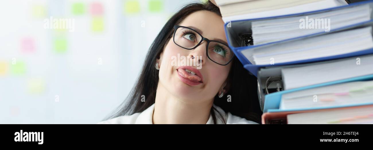 Müde junge Frau, die am Schreibtisch saß und viele Dokumente aus der Nähe hatte Stockfoto