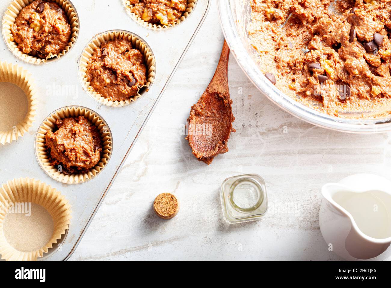 Draufsicht Bild zeigt die Herstellung von köstlichen Obst und Nusskuchen auf weißem Marmor Arbeitsplatte Hintergrund. Muffin-Dose mit Liner, Zutaten und Utensi Stockfoto