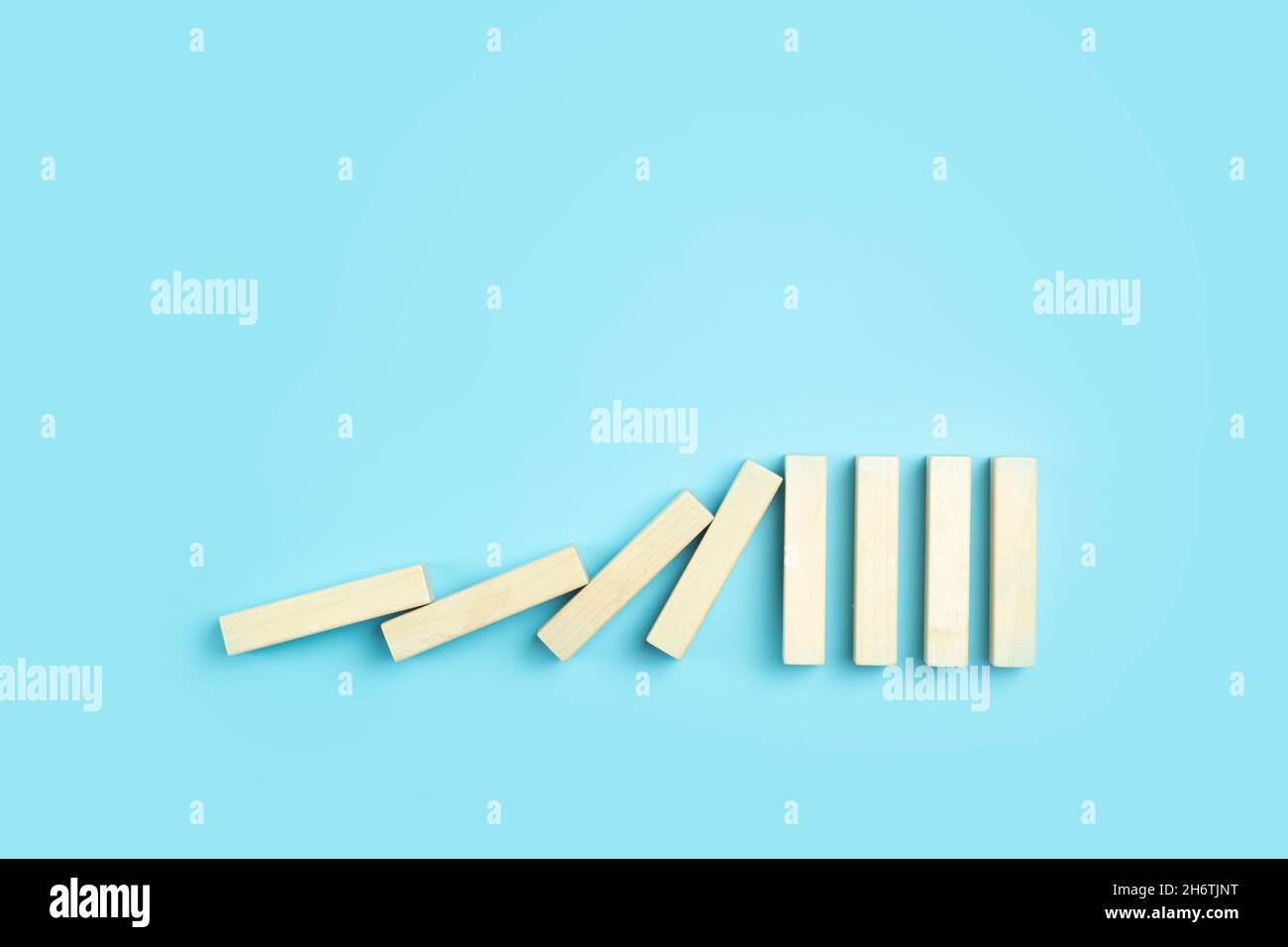 Fallende Dominosteine auf einem sauberen blauen minimalen Hintergrund. Geschäfts-, Risiko-, Management- und Finanzkonzept. Hochwertige Fotos Stockfoto