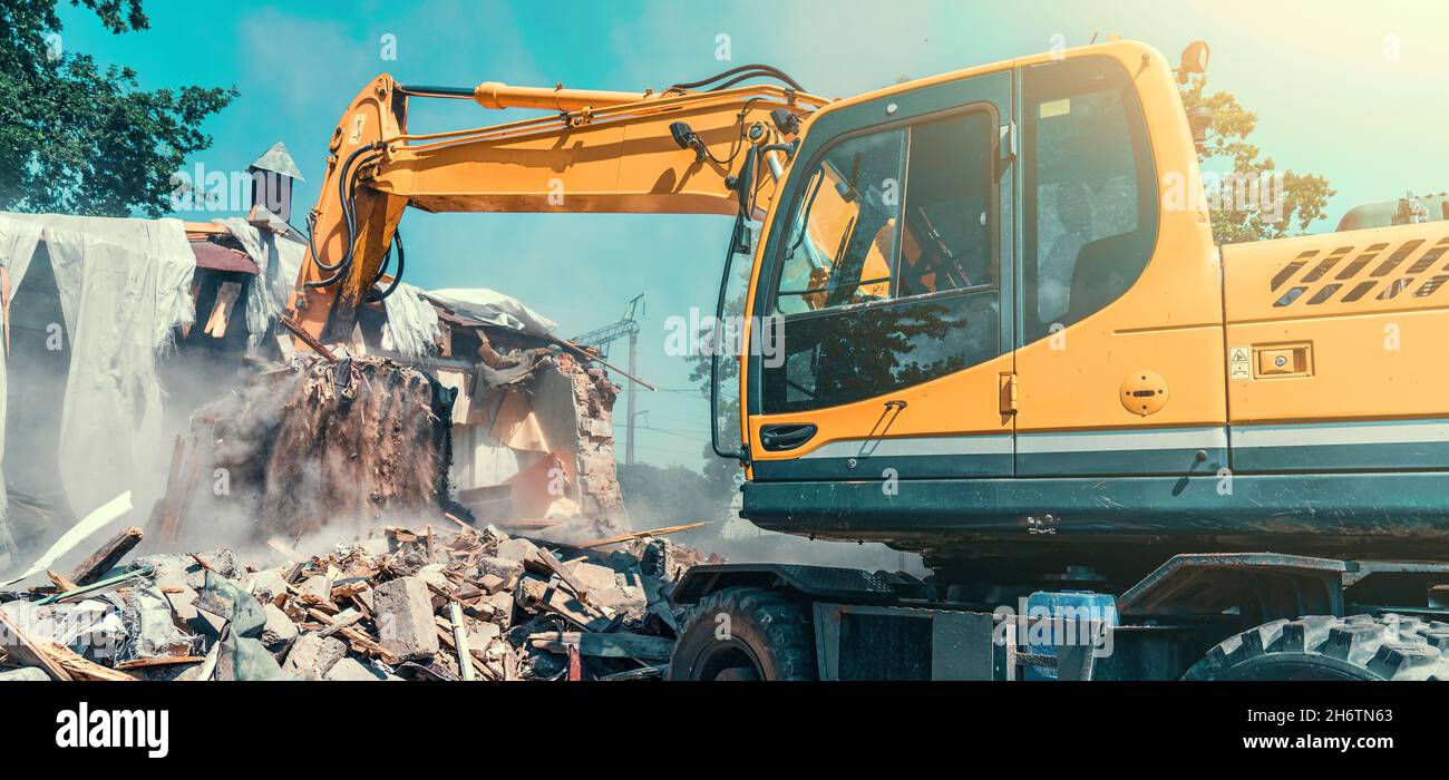 Bagger Demontage Haus auf Baustelle. Abriss von baufälligen Wohnungen für Neuentwicklung. Stockfoto