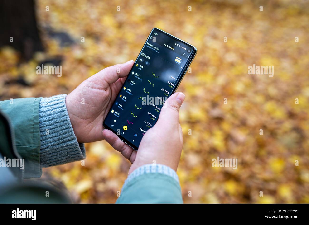 Binance App auf dem Smartphone in den Händen der Frau mit verwackelten gelben Herbstlaub Hintergrund. Kryptowährungsbörse, Handelsplattform. Selektiver Fokus. Warschau, Polen - 19. Oktober 2021 Stockfoto