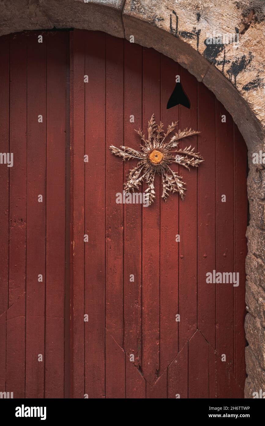 Europäische Retro-Holztür und Steinwand Hintergrund mit einer trockenen Blumendekoration Stockfoto