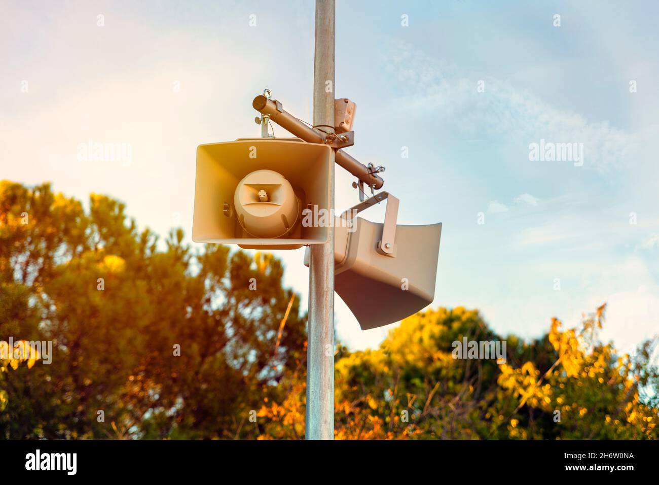 Zwei Lautsprecher auf einem Mast im Park bei Sonnenuntergang zur Information Stockfoto