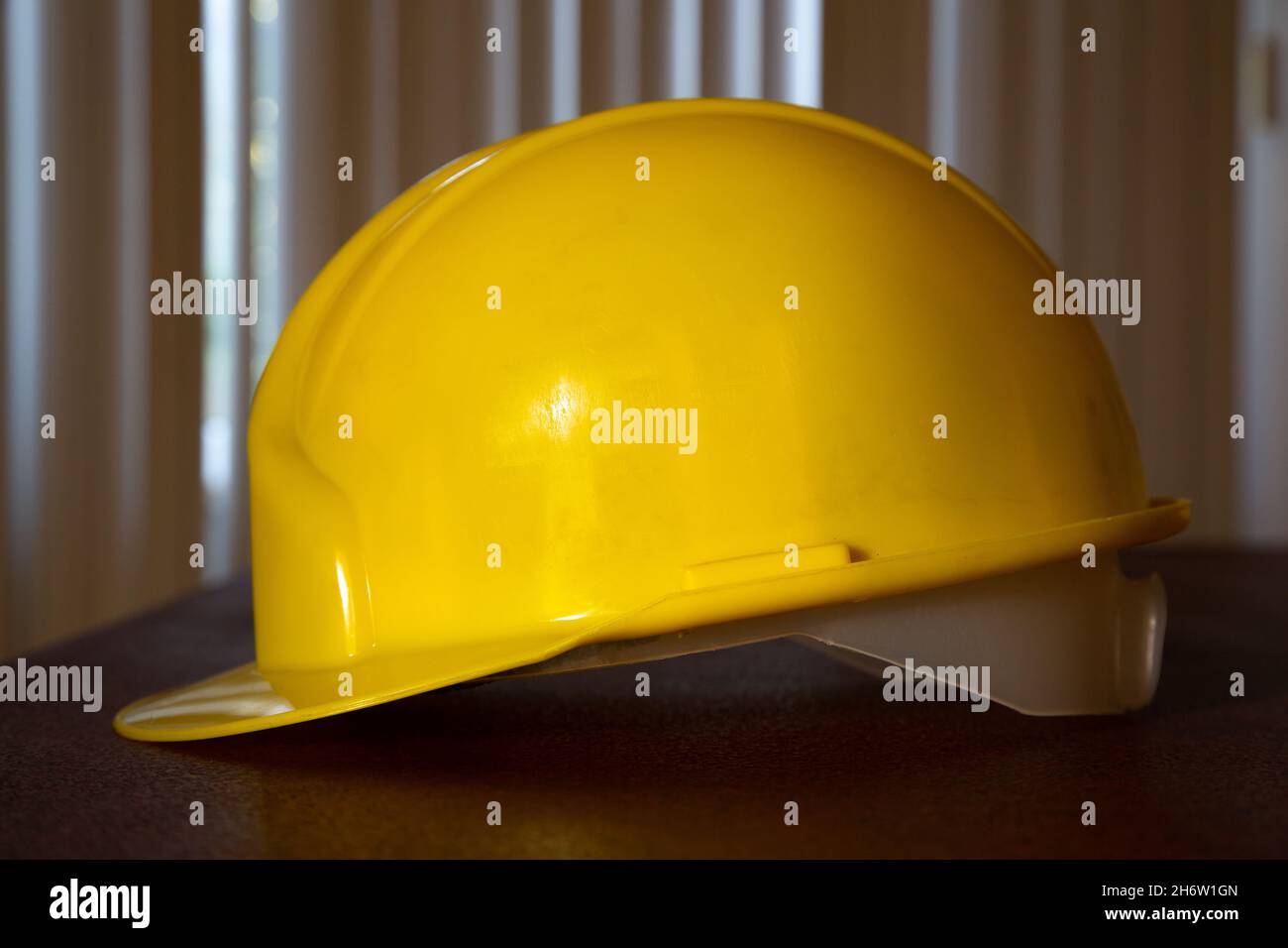 Gelber Schutzhelm auf dem Tisch. Seitenansicht des gelben Schutzhelms. Stockfoto