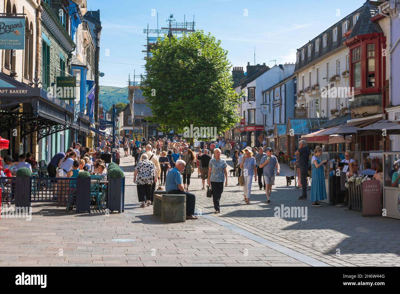 Keswick Stadtzentrum, Blick auf einen Sommertag voller Menschen, die an Cafés in der Main Street, Keswick, Cumbria, England, entspannen oder einkaufen gehen Stockfoto