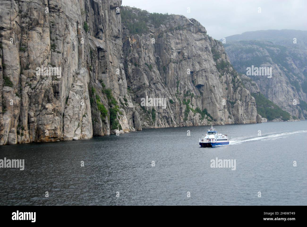 Passagierfähre in Fjord entlang steiler und hoher Felswand, Norwegen Stockfoto
