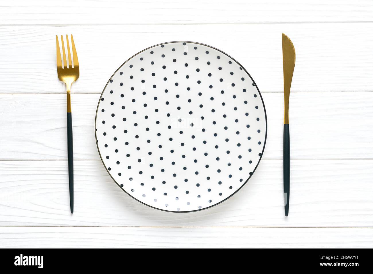 Leere weiße runde Platte mit schwarzen Erbsen, Gabel, Messer, Löffel auf Holztisch Draufsicht flache Lay-Gerichte zum Frühstück, Mittag- oder Abendessen Mock up. Stockfoto
