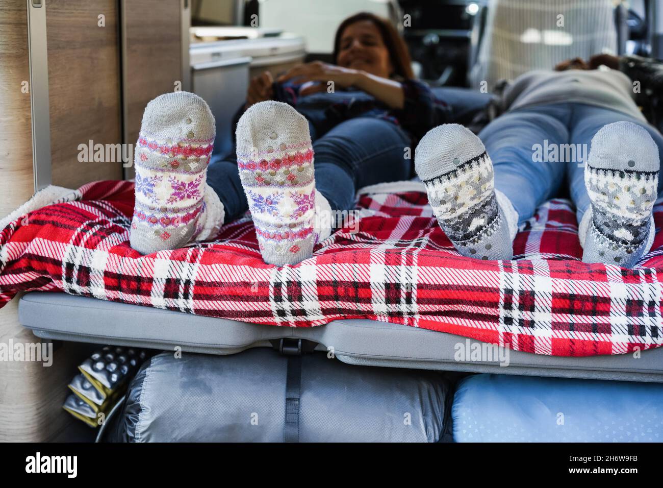 Reife Frauen schlafen im Mini-Van Camper tragen warme Weihnachtssocken - Fokus auf Füße Stockfoto