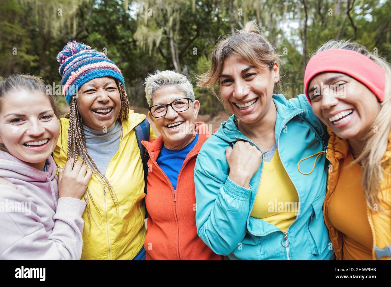 Multirassische Freundinnen, die während des Trekkingtages im Wald Spaß haben - konzentrieren Sie sich auf das Gesicht der mittleren Senioren Stockfoto