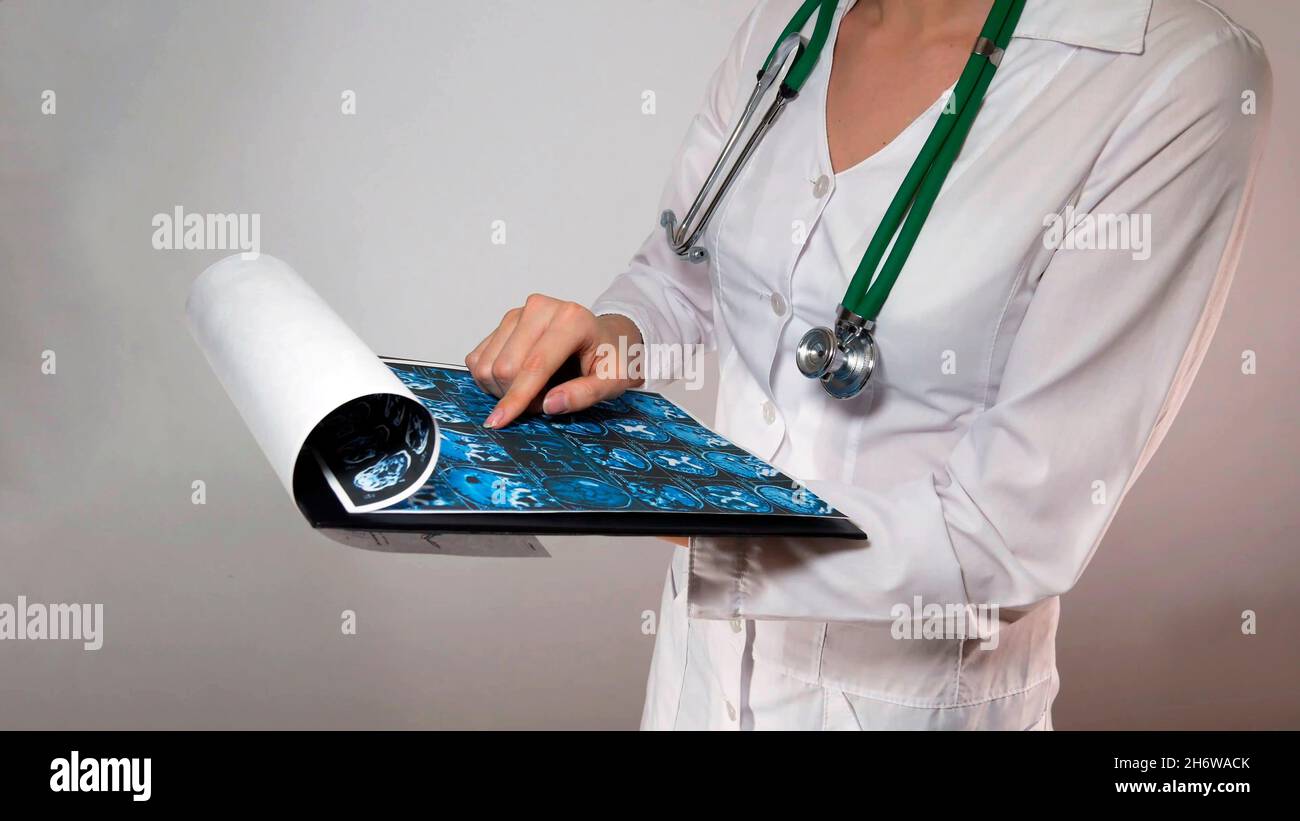 Nahaufnahme einer Ärztin mit einem Stethoskop im Hals, bei der die Diagnose einer Hirnröntgenaufnahme einer Patientin gestellt wird. Stockfoto